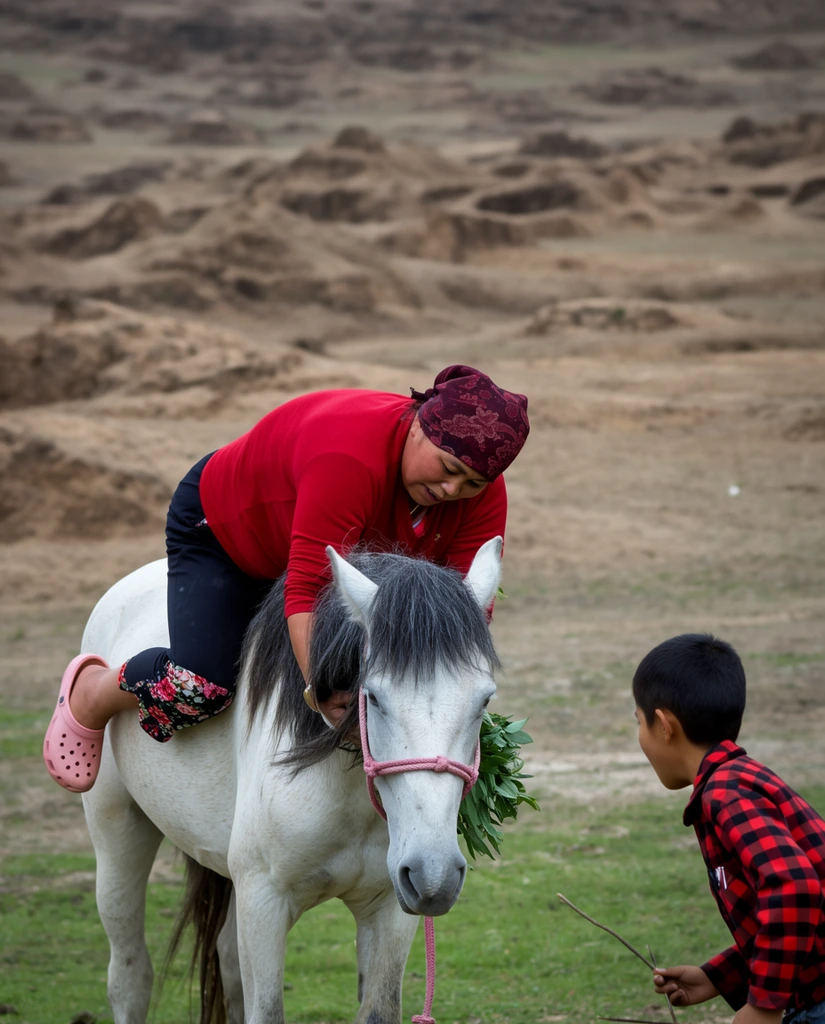 A woman in vibrant red clothing mid-dismount from a white horse in a rugged landscape, closely observed by a young boy. The woman wears a crimson long-sleeved shirt, dark trousers with floral cuffs, pink slip-on clogs, and a patterned maroon headscarf. She leans awkwardly across the horse's back, gripping its dark grey mane to steady her downward slide. The horse stands calmly, outfitted with a pink rope halter and a bundle of green leaves tucked near its snout. In the lower right, a boy in a red-and-black checkered shirt leans forward with a thin stick, watching her descent intently. The foreground features patchy green grass that fades into an expansive, softly blurred background of dry, undulating brown earth and rugged mounds under diffuse, natural daylight.