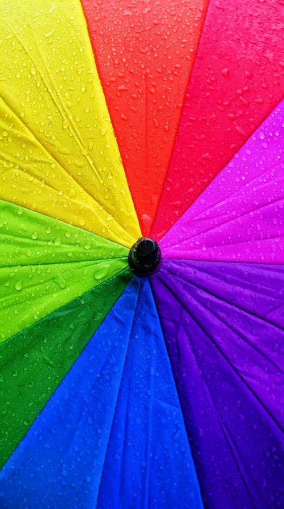 top-down close-up of a vibrant rainbow umbrella canopy, radial composition of triangular fabric panels in vivid yellow red magenta purple blue and green, heavily beaded with scattered clear water droplets, central small black cap, specular highlights on wet nylon texture, macro photography, high saturation