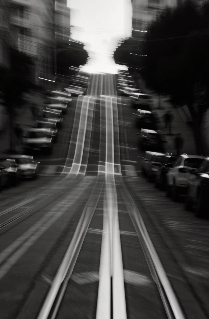 cinematic black and white fine art photography, heavy horizontal motion blur, grainy film texture, high contrast noir aesthetic, a steep urban street with central tram tracks, rows of parked cars along the curbs, long exposure intentional camera movement, ethereal and ghostly light streaks, deep shadows and soft highlights, moody atmospheric abstraction, evocative of a fleeting memory or dreamlike urban landscape.