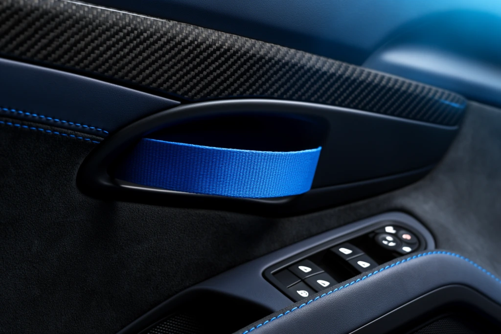 sports car door interior macro, blue fabric pull strap handle, carbon fiber trim, black suede panel, dark leather with blue contrast stitching, matte black bezel, window controls, dramatic cool lighting, shallow depth of field, crisp textures