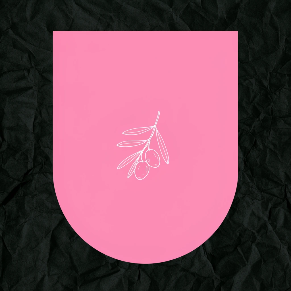 A large, flat pink geometric shape with a straight top and rounded base dominates a dark, heavily creased background resembling textured black paper. Centered on the bright pink form is a delicate white line-art drawing of a small branch bearing two olives and leaves.