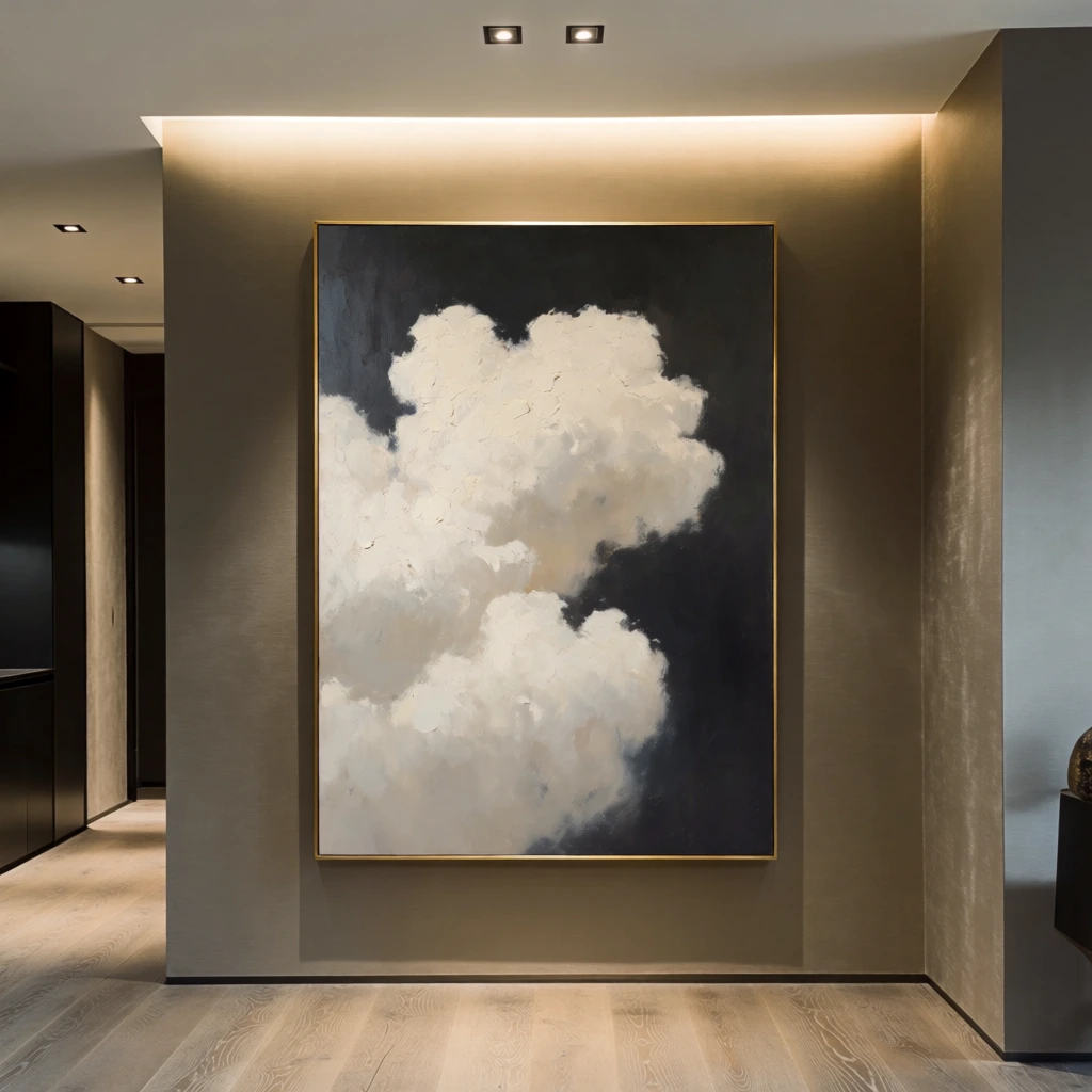 A large, vertical abstract oil painting of a billowy white cloud against a dark background is the focal point of a modern, minimalist interior hallway. The painting, encased in a thin gold frame, features a thick, textured formation of off-white and cream-colored clouds that dominate the center and left side of the canvas, rendered with soft, painterly brushstrokes. The background of the artwork is a deep charcoal or near-black color, providing a high-contrast backdrop for the bright cloud formation. The artwork is mounted on a taupe or warm gray wall that has a subtle sheen. Below the painting, light-colored wooden floorboards with a visible grain run horizontally. To the left of the main wall, a narrow hallway reveals dark cabinetry and a glimpsed doorway with recessed ceiling lights. The ceiling above the painting is recessed and features a warm, hidden LED light strip that casts a soft glow downward, as well as two small, square recessed spotlights. To the right, the wall forms a corner, and a small portion of a dark object is visible at the very edge. The overall color palette is a sophisticated mix of warm neutrals, deep blacks, and gold accents, creating a calm and contemporary atmosphere through a medium-shot, eye-level perspective.