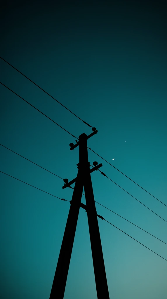A stark black silhouette of a utility pole with an A-frame base and crossarms stands against a deep teal gradient sky. Taut power lines cut diagonally across the frame, creating geometric tension. A tiny crescent moon and a faint star hang in the smooth cyan expanse to the right. The low-angle minimalist composition emphasizes the high contrast between the dark industrial structure and the rich twilight background.