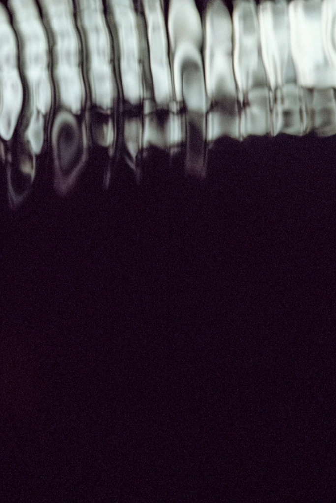 An abstract, high-contrast composition dominated by a deep, granular darkness in its lower two-thirds. Along the top edge, a row of luminous, wavy vertical bands creates the appearance of bright light heavily distorted through rippling water or warped glass. These pale, irregular streaks of ghostly white and soft grey transition abruptly into a dense, solid expanse of deep purple-black. The cinematic framing features heavy film grain and a pronounced optical ripple effect, warping the boundaries of the illuminated shapes to establish a fluid, obscure atmosphere.