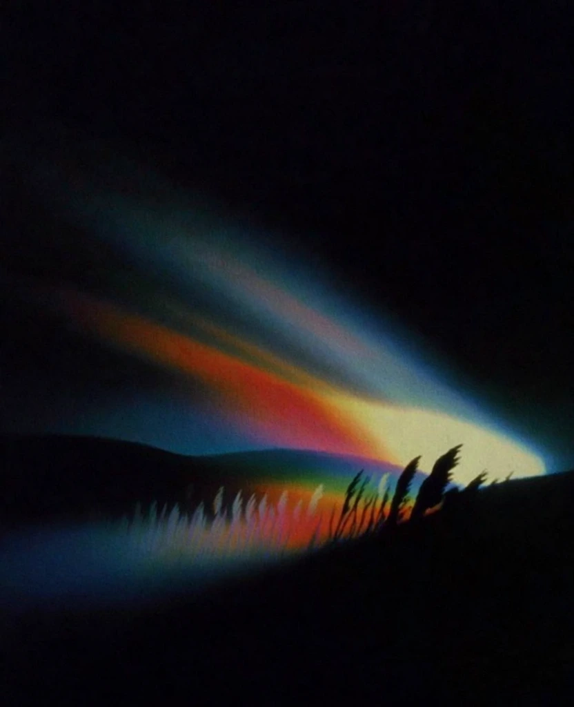 hazy minimalist landscape with silhouette flora of tall swaying grass and distant hills against a pitch-black liminal void, dramatic prismatic light dispersion cutting through the scene in diagonal volumetric beams, vibrant spectrum of crimson and cyan and amber light leaks, heavy analog film grain texture, soft-focus ethereal bloom, vintage 1970s experimental photography aesthetic, high-contrast chiaroscuro, dreamlike atmospheric haze, glowing rainbow-spectrum god rays.