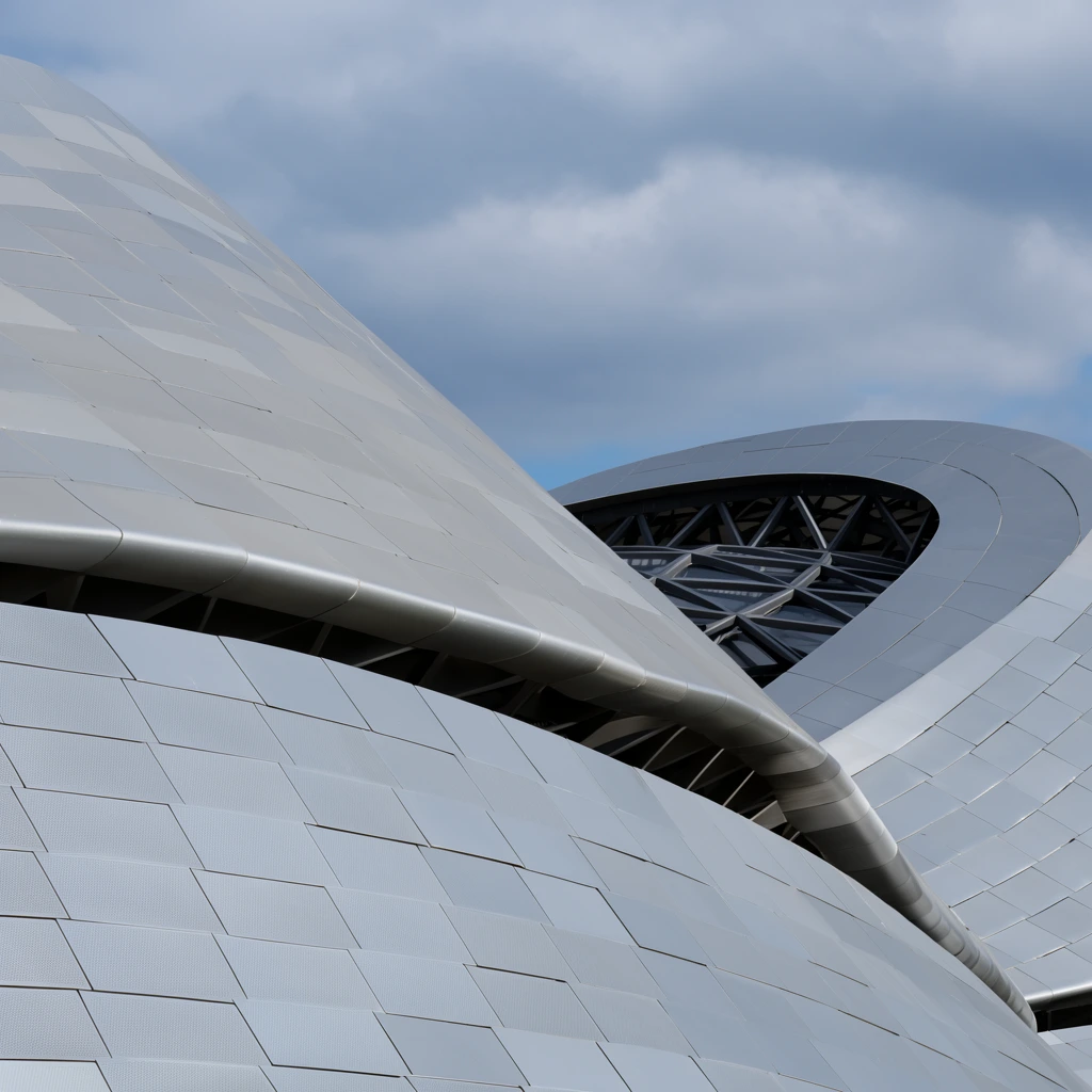 close-up of modern curvilinear architecture, sweeping overlapping metallic forms, light grey exterior panels in a staggered grid, subtle perforated surface texture, dark geometric steel truss framework visible through a gap between undulating sections, cloudy blue and grey sky background, natural daylight, low angle perspective, sleek futuristic design
