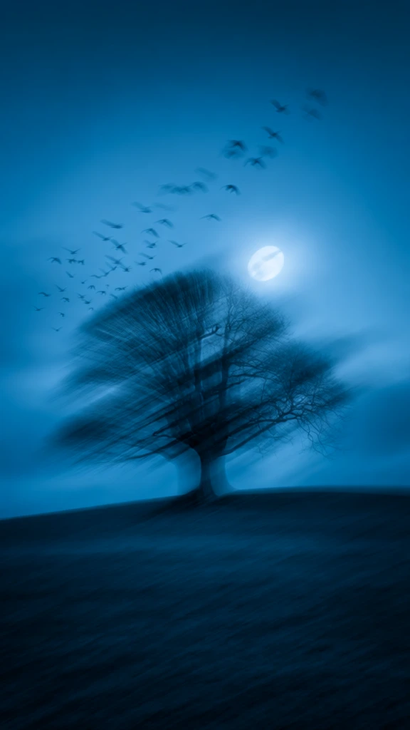 long exposure intentional camera movement of a single bare tree on a gentle slope, flock of birds ascending toward the upper right, glowing full moon in a clouded sky, monochromatic cerulean and deep cyan palette, extreme horizontal and diagonal motion blur streaks, ethereal painterly texture, high-key highlights dragging across the frame, silky diffuse light, abstract landscape with heavy directional drag, minimalist composition with a sense of fluid velocity, cinematic blue wash