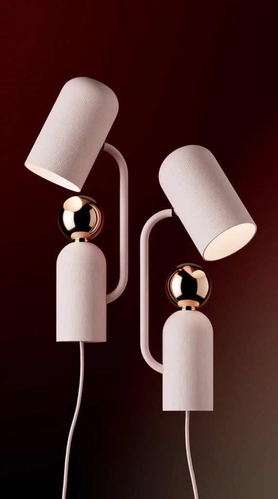Two contemporary pale pink table lamps with reflective rose gold spherical joints float against a deep crimson to dark brown gradient background. Each minimalist lamp features a vertical cylindrical base with a finely ribbed texture, topped by a highly polished, mirror-like rose gold sphere. A slender, curved tubular arm extends from the base to support a matching ribbed cylindrical shade. The left lamp's shade points upwards, illuminating the metallic sphere, while the right lamp leans forward with its shade angled down to reveal a gently glowing interior. Smooth pale pink cords trail from the bottom of each base. The high-end photorealistic product rendering uses pristine studio lighting to emphasize the stark contrast between the soft matte pastel surfaces, the warm metallic accents, and the moody, rich background.