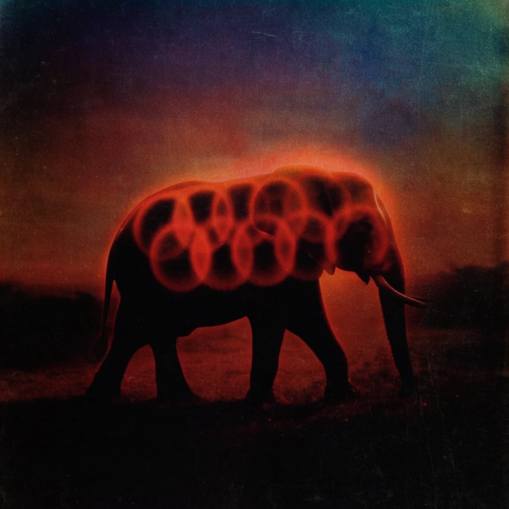 An elephant walks across a shadowed plain, bearing prominent overlapping circular patterns across its back. Heavy pitch-black darkness consumes the foreground and the lower extremities of the elephant, contrasted by an intense, ethereal blood-orange and fiery crimson glow radiating from behind the animal and bleeding into the circular patterns with a spectral, hazy luminescence. The background sky transitions from murky rust-red near the obscured horizon to a deep, bruised indigo and dark teal at the top edge. The overall visual treatment features heavily distressed vintage film grain, soft-focus optical blurring, glowing red halation around the subject's edges, extreme chiaroscuro, dark framing vignettes, and the textured, macabre finish of aged, experimental 1970s analog photography.
