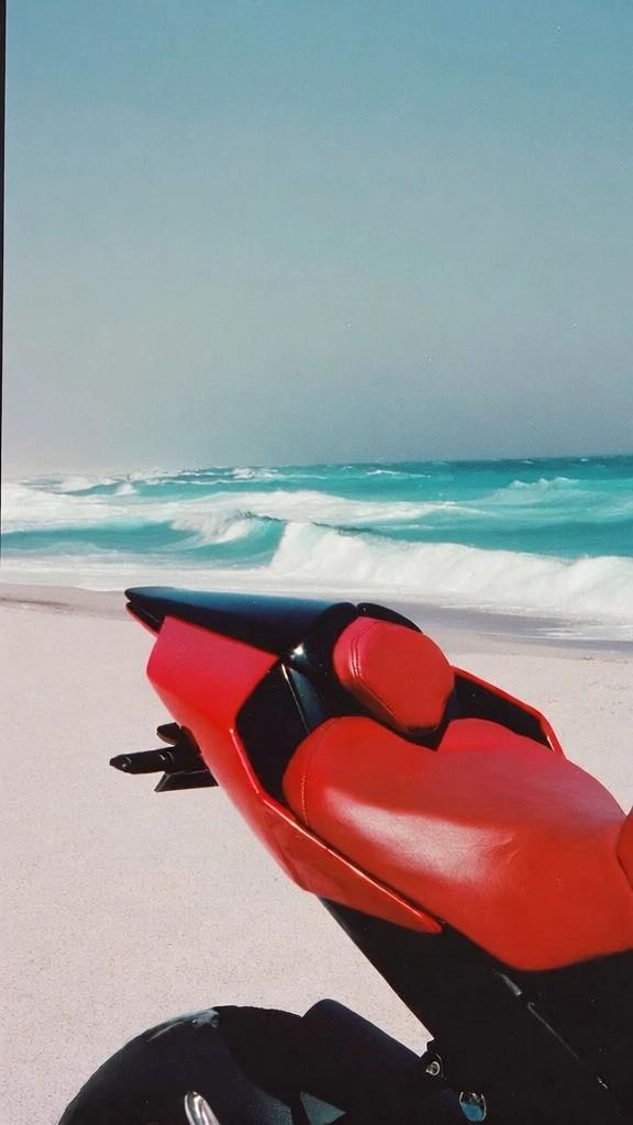cinematic 35mm film photography, grainy texture, rear section of a sleek black motorcycle with a sharp pointed tail and a vibrant red leather seat, centered on a wide expanse of white sand beach, turquoise ocean waves crashing in the background under a clear blue sky, high contrast midday sunlight with deep shadows, minimalist surreal editorial composition, saturated pop-art color palette of fire engine red, deep black, and crisp whites, lo-fi aesthetic.