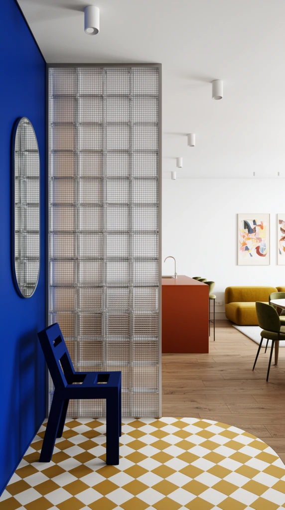 dark blue geometric chair on mustard yellow and white checkerboard tiles, tall glass block divider with internal wire mesh, cobalt blue wall with a pill-shaped mirror, floor curving seamlessly into natural wood planks, background living space featuring a rust-orange counter, mustard yellow sofa, olive green dining chairs, abstract art on crisp white walls, cylindrical ceiling lights, postmodern interior design, bright color blocking, architectural photography