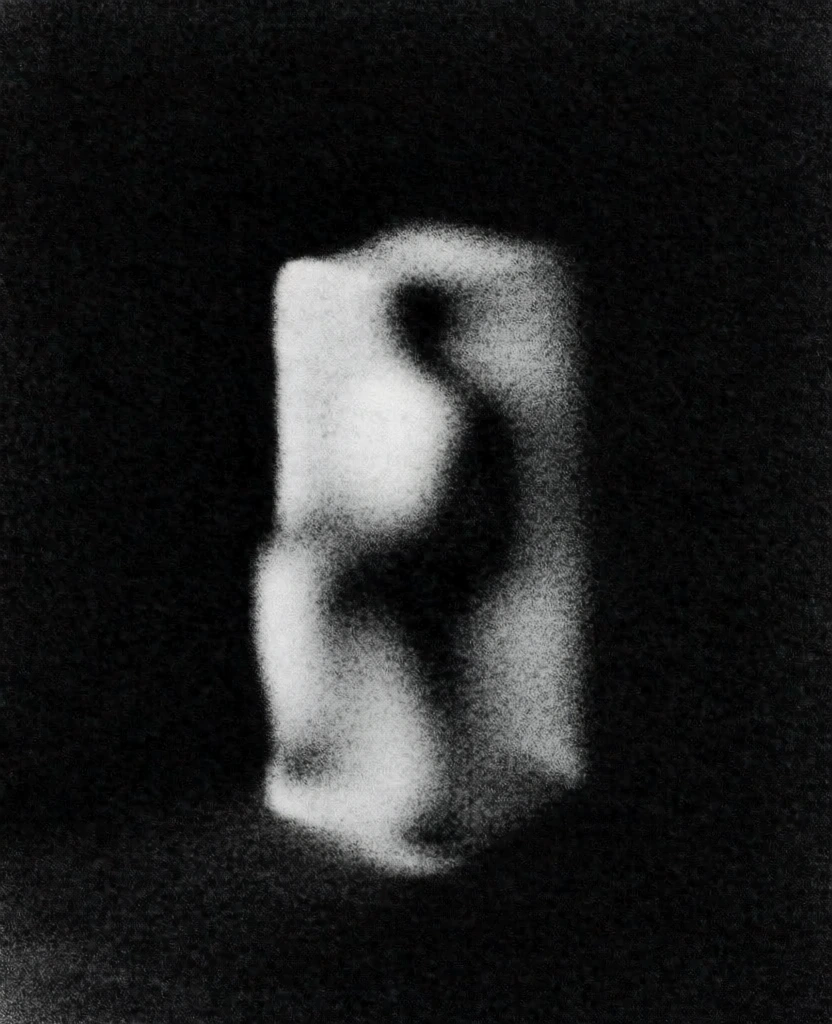 a tall monolithic rectangular block standing in a shadowed room corner, rendered in extreme high-contrast monochrome with heavy stippled film grain and gritty lithographic noise, stark chiaroscuro lighting causing the form to glow softly against a pitch-black void, ethereal soft-focus edges with a hazy sfumato blur, minimalist composition, deep negative space, tactile pointillist texture, somber and evocative atmosphere, non-literal light diffusion, high-iso analog film quality.