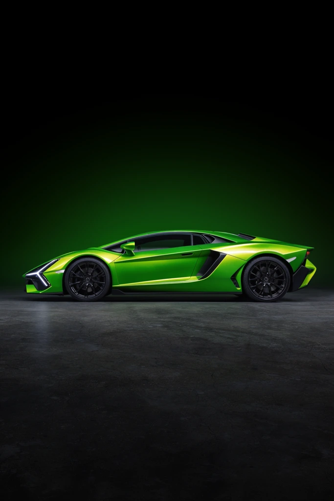 A vibrant neon-green hypercar is captured in sharp side profile against a moody studio backdrop. The wedge-shaped vehicle features an aggressive aerodynamic design with deep side air intakes, sharply creased fenders, and large black multi-spoke alloy wheels. Distinctive Y-shaped LED lights illuminate the angular front, while the highly reflective metallic paint catches intense specular highlights along the faceted doors and sloping roofline. The car rests on a dark, textured concrete surface, framed by a subtle emerald light gradient fading upward into a stark black void directly behind its sleek silhouette. Shot with high-end automotive studio lighting, the high-contrast, dead-on composition emphasizes the striking, futuristic industrial aesthetic.