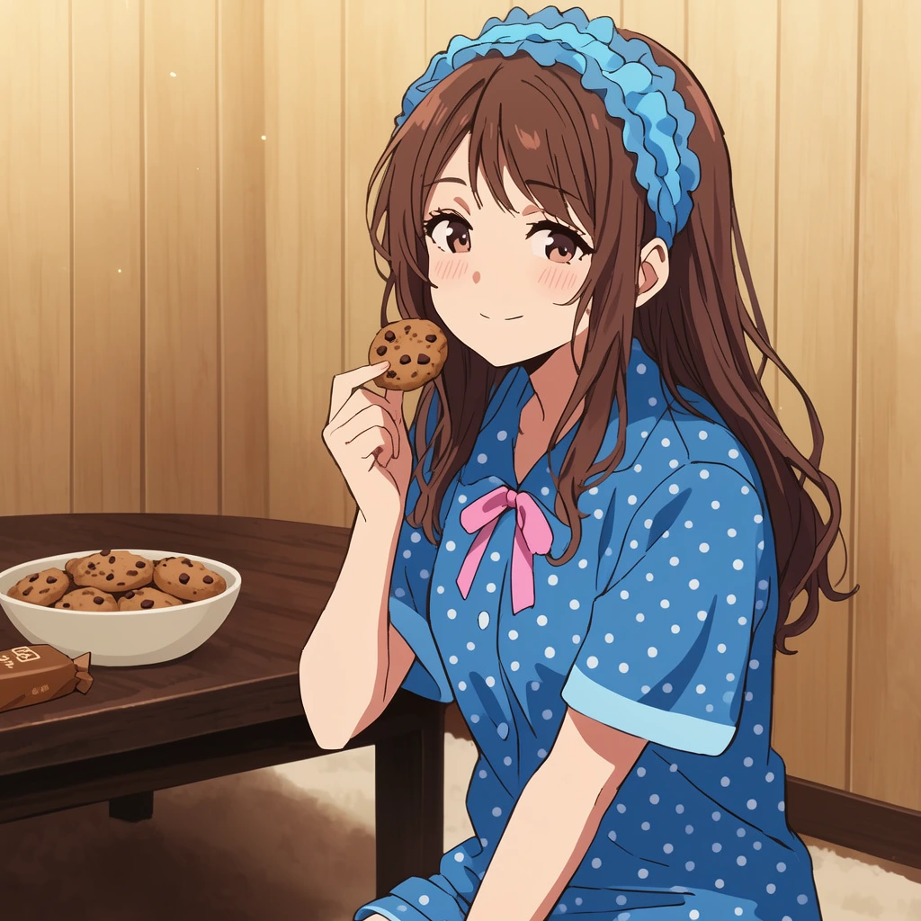 A young woman with long brown hair and a blue ruffled headband sits holding a chocolate chip cookie near her faintly blushing, smiling face. She wears blue short-sleeved pajamas with white polka dots and a pink collar ribbon. Beside her, a dark wooden table holds a bowl of cookies and a brown package against light wood-paneled walls. The scene is a 2D digital anime illustration featuring warm ambient lighting, soft shading, and a cozy, inviting atmosphere.