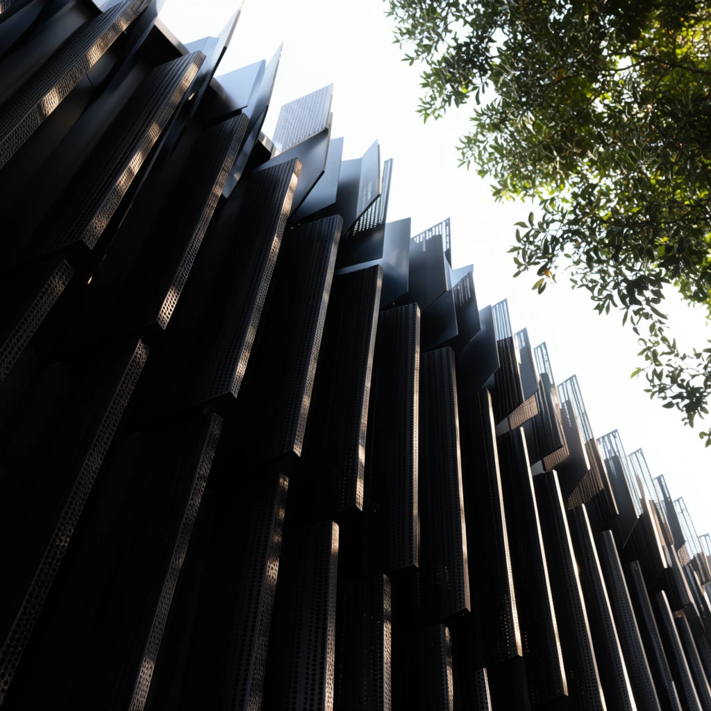 modern dark architectural facade, repeating vertical perforated metal louvers, overlapping geometric panels, sunlight highlighting textured edges, deep shadows, low angle looking up at bright white sky, green tree leaves at top right, high contrast architectural photography