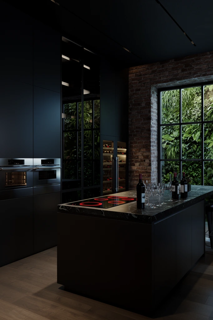 A modern dark kitchen featuring matte black cabinetry and a large marble island. The foreground island holds an electric cooktop with glowing red elements, wine bottles, and clear glasses. Leftward, seamless cabinets frame stacked stainless steel ovens. Reflective glass doors and an illuminated wine refrigerator add deep background dimensions. Rightward, an exposed brick wall meets a large grid window revealing a lush vertical green garden. Dramatic low-key architectural lighting emphasizes sleek textures and contrasts the moody interior with vibrant exterior foliage.