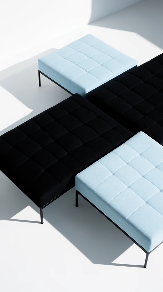 High-angle minimalist studio photography of modular grid-patterned seating on a stark white floor. Thick tufted square cushions in deep black and pale blue fabric rest on thin black legs. Harsh directional lighting casts sharp geometric shadows across the pristine ground, emphasizing extreme contrast and architectural precision.