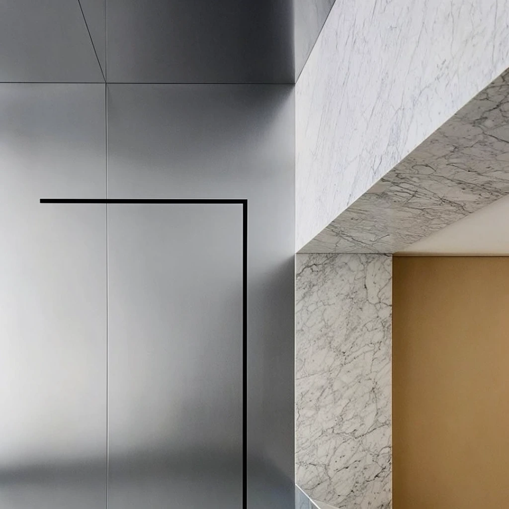 Minimalist interior architecture defined by contrasting materials and precise geometric planes. Large panels of smooth, reflective grey metal dominate the left, separated by fine vertical seams and featuring a stark black geometric graphic composed of sharp perpendicular lines. To the right, structural elements of white marble with delicate grey veining form angular transitions, framing a recessed opening that reveals a flat, warm beige interior wall. Soft, diffused ambient lighting casts subtle gradients across the metallic surfaces while highlighting the crisp edges of the stone. The asymmetrical, low-angle composition emphasizes clean modernist lines and the bold juxtaposition of cool metallic finishes against patterned natural stone and warm earthy accents.