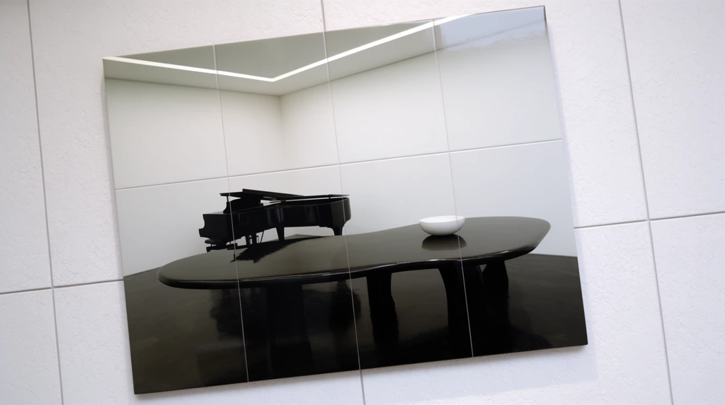 A glossy tiled artwork hangs at a tilted angle against a textured white gallery wall, constructed from a grid of square panels with visible intersecting seam lines. The picture depicts a stark, minimalist room featuring smooth white walls, a striking linear ceiling light, and a dark, highly reflective floor. A glossy black grand piano and an expansive, irregularly shaped black table dominate the sterile space, casting sharp reflections on the ground. A small, smooth white bowl rests on the polished dark surface of the table. The interior composition emphasizes a dramatic contrast between the bright, expansive upper half of the room and the heavy, shadowed lower half, evoking a quiet, liminal atmosphere.