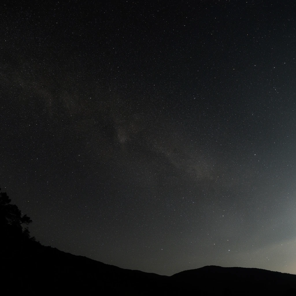 vast night sky filled with countless glowing stars, faint hazy dust band stretching diagonally across the dark expanse, pitch black silhouette of a rolling mountain range along the bottom edge, jagged tree silhouettes on the far left peak, deep black and dark gray tones, crisp white stellar pinpoints, faint atmospheric glow near the right horizon, long exposure astrophotography, wide-angle perspective