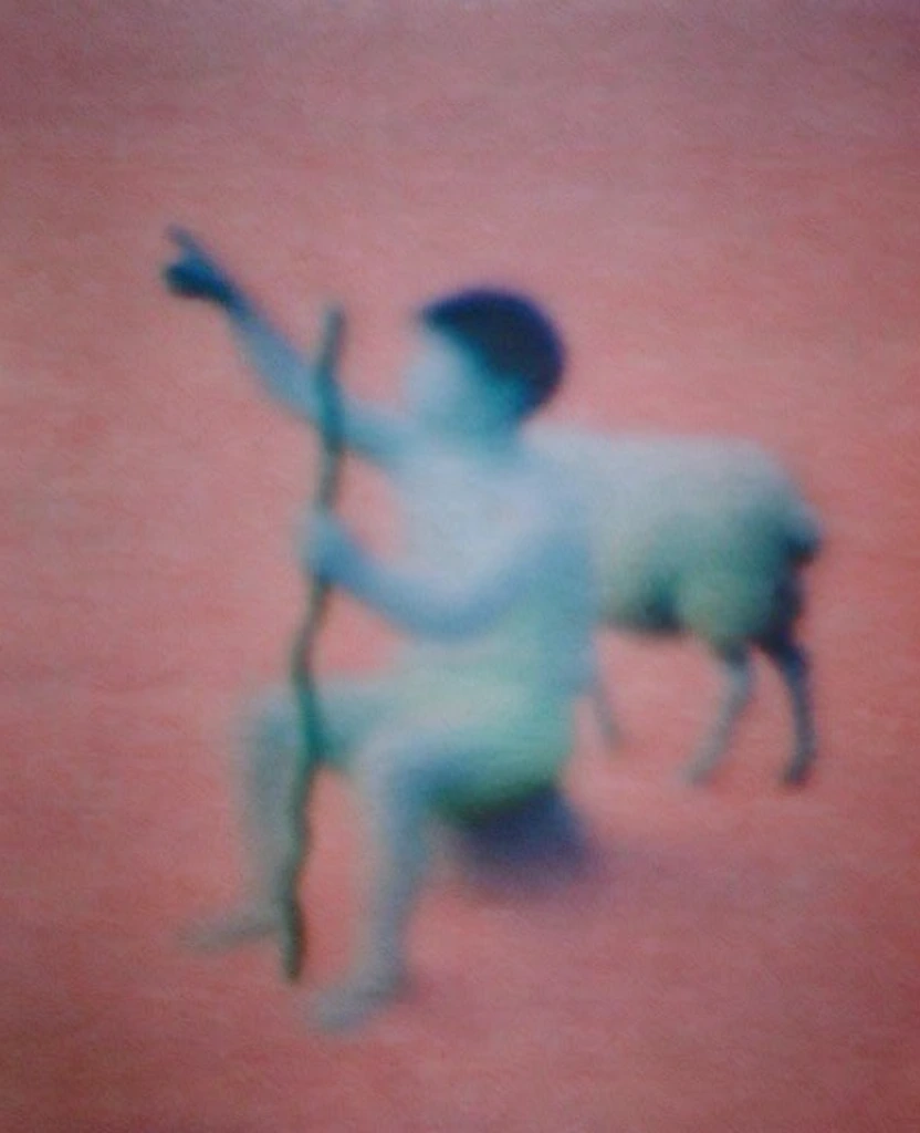 ultra-soft focus and heavily blurred composition, dreamlike impressionistic aesthetic with no sharp edges, a young boy sitting with arm raised pointing upward, he holds a wooden staff, a sheep stands behind him to his right, background of dark foliage and ground, moody atmospheric lighting, silhouettes bleeding into the environment, cinematic grain, minimalist framing, muted ethereal color palette, ghostly quality, hazy texture, light and shadow rendered as soft blobs of diffused color.