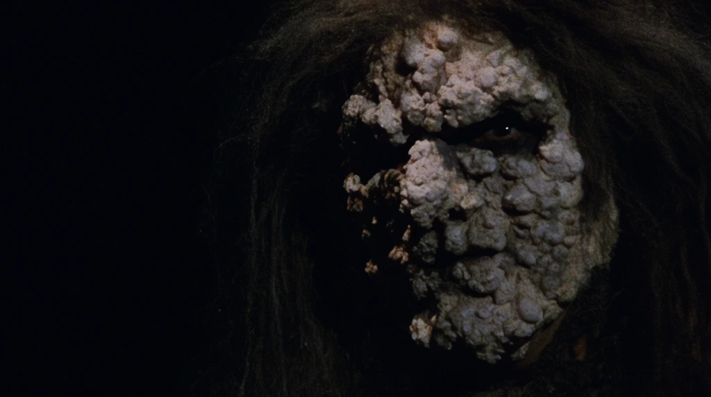 A grotesque humanoid face covered in a pale, heavily textured, lumpy crust emerges from stark, pitch-black darkness. The visage features thick, asymmetrical clusters of rough, stony protrusions that obscure normal anatomical structures. Deep-set eye sockets are heavily shadowed, with a single dark eye barely visible within the crevices. Coarse, dark, matted hair frames the crusted face, dissolving into the surrounding void. Extreme low-key lighting creates a harsh chiaroscuro effect, intensely illuminating the right side of the face while the left side falls entirely into shadow. The composition features a gritty vintage film grain, evoking a moody, practical-effects horror aesthetic that emphasizes the unsettling, tactile quality of the creature.