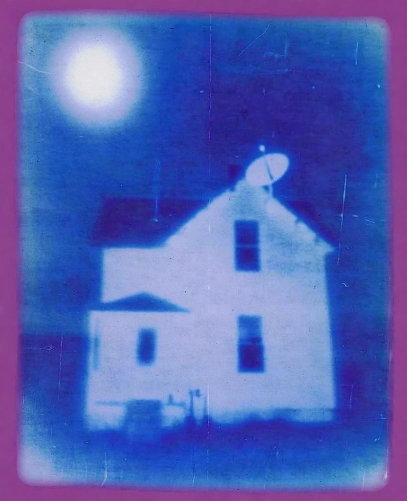 a two-story house with a satellite dish, rendered in a haunting lo-fi cyanotype aesthetic, monochromatic blue and white palette with a thick magenta border, heavy film grain, scratches, analog noise, ethereal bloom, soft glow emanating from the structure, glowing white orb in the upper left corner, blurred edges, heavy vignette, surreal liminal atmosphere, high-contrast silhouette against a hazy background, minimalist composition, 1990s experimental photography style.