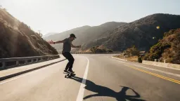 A man skateboarding fast down a hill street in San Francisco, clear skies, side view.