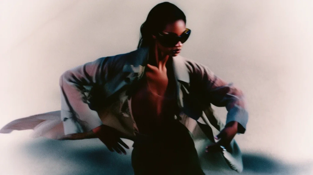 Fashion model dynamic pose, low vantage point, trench coat and sunglasses, action shot